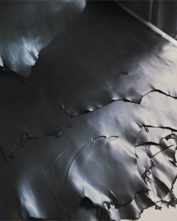 Pile of dark leather pieces in our leather craft warehouse.