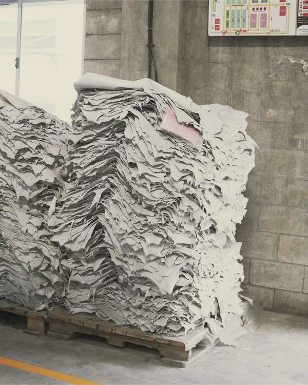 Two big piles of light grey leather pieces stored in our leather craft warehouse.