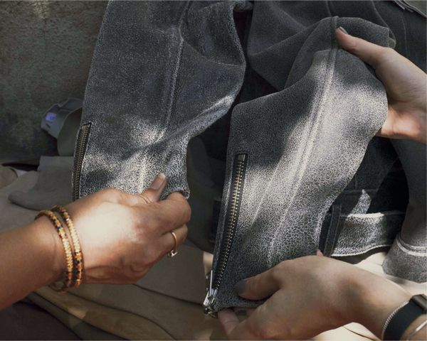 Close up on one of our leather jacket held by two of our leather artisans.