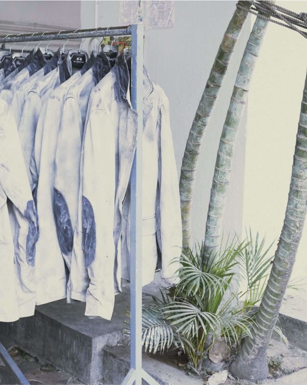 Several menswear lether jacket are hanging on a clothes rack.