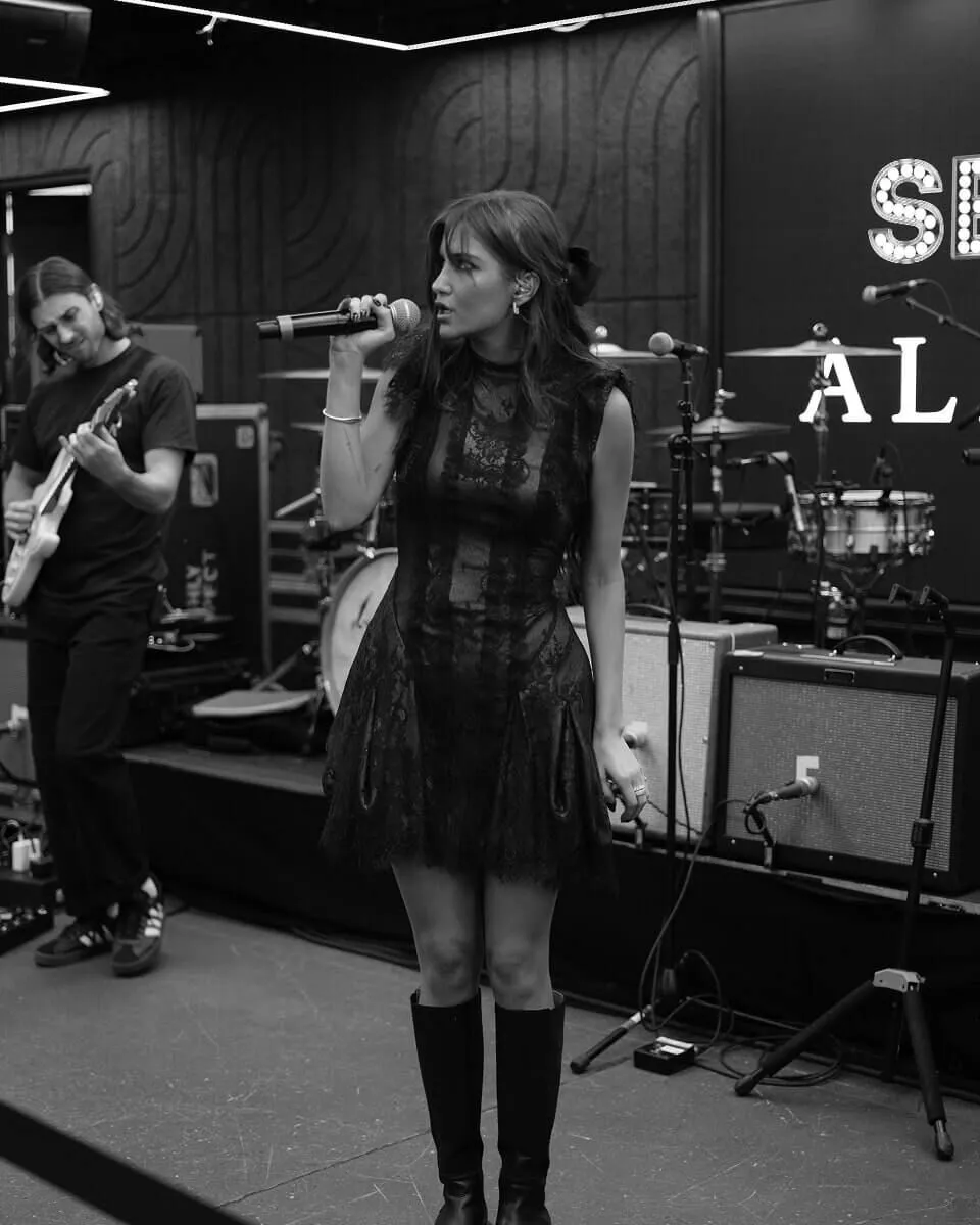 Greylin James Rue singing and wearing a lace black mini dress