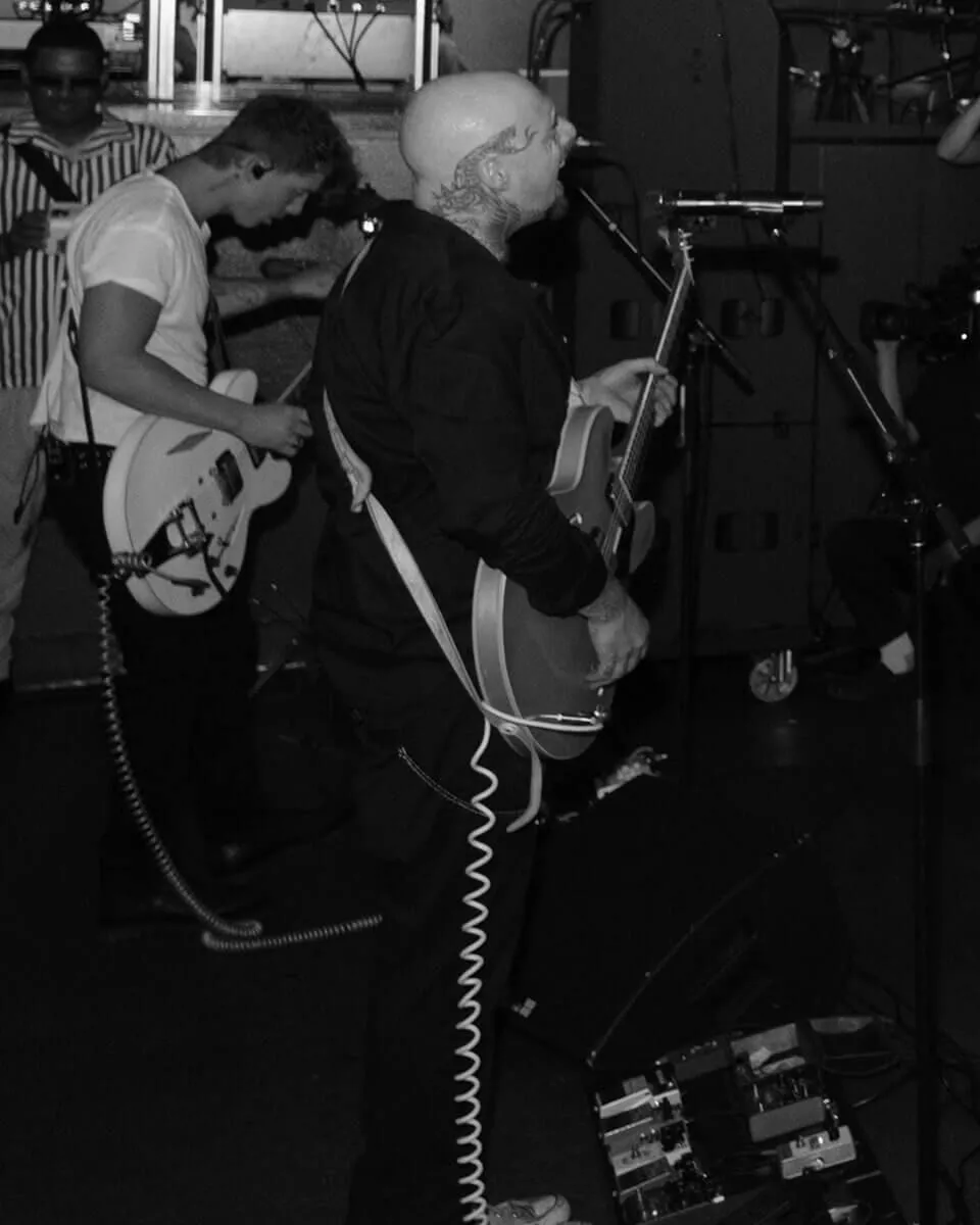 Two men playing guitar and singing into microphones