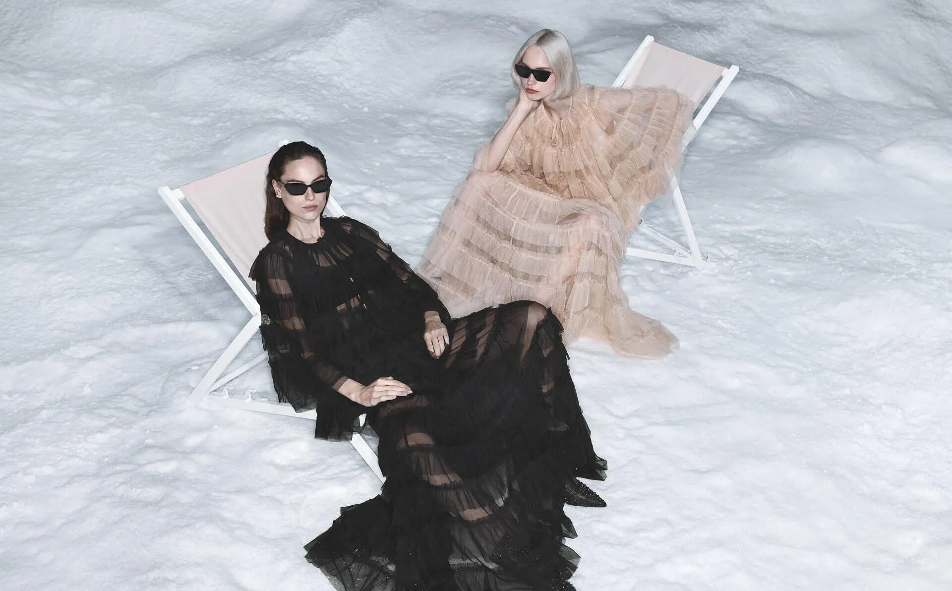 two women sat in deck chairs on snow