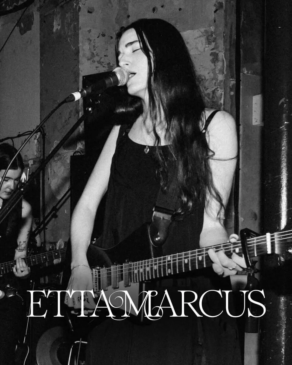 Black and white closeup shot of Etta Marcus front singer on stage singing into a microphone.