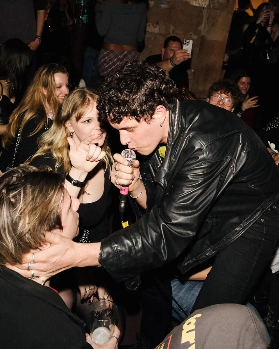 LEAP singer wearing a leather jacket, holding an audience members face