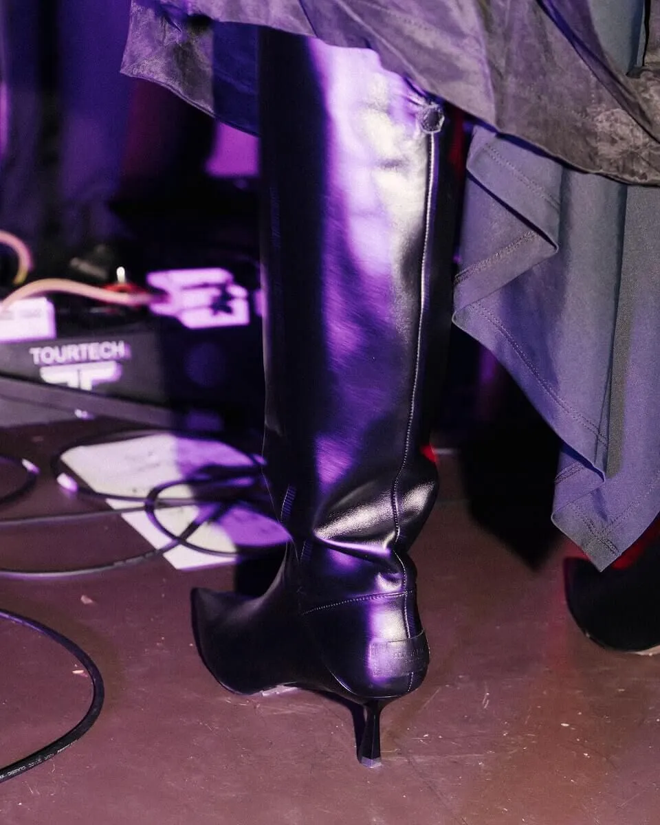 Closeup shot of the back of a black knee-high heeled boot.