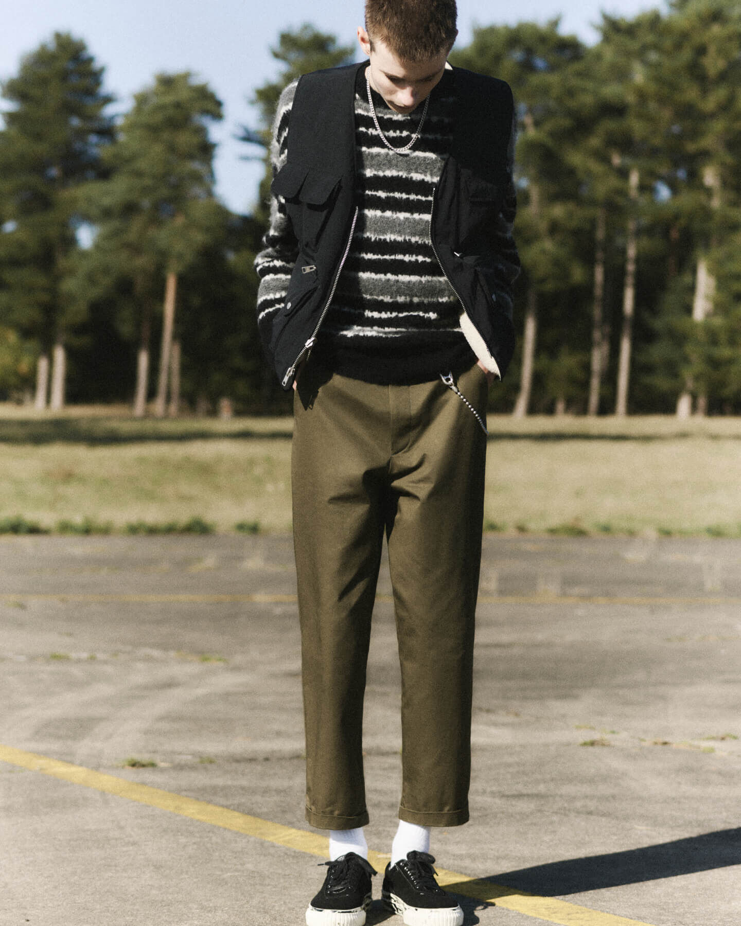 Man wearing a striped jumper, green trousers and black gilet