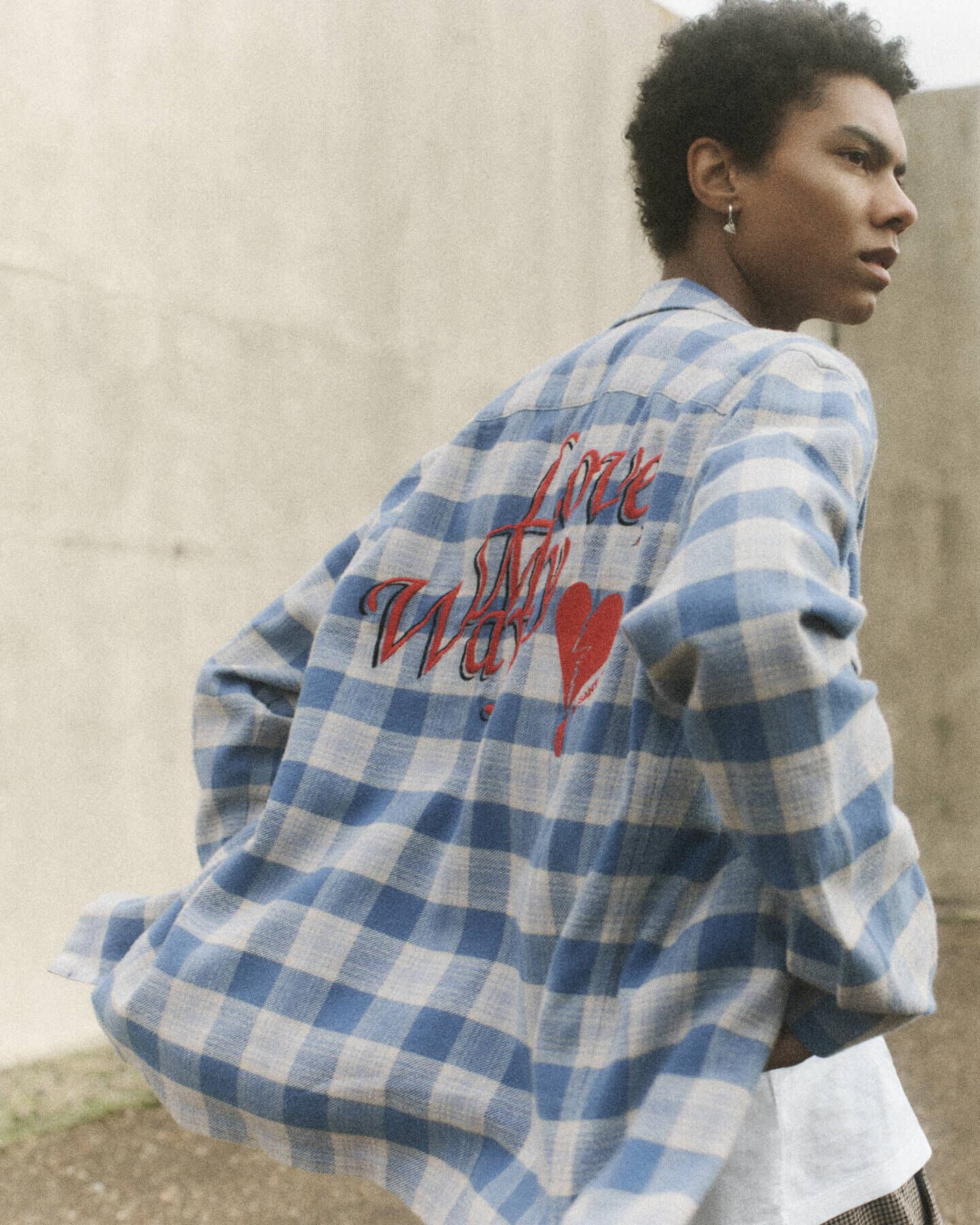 Man wearing a green blue and white checked shirt with red graphic