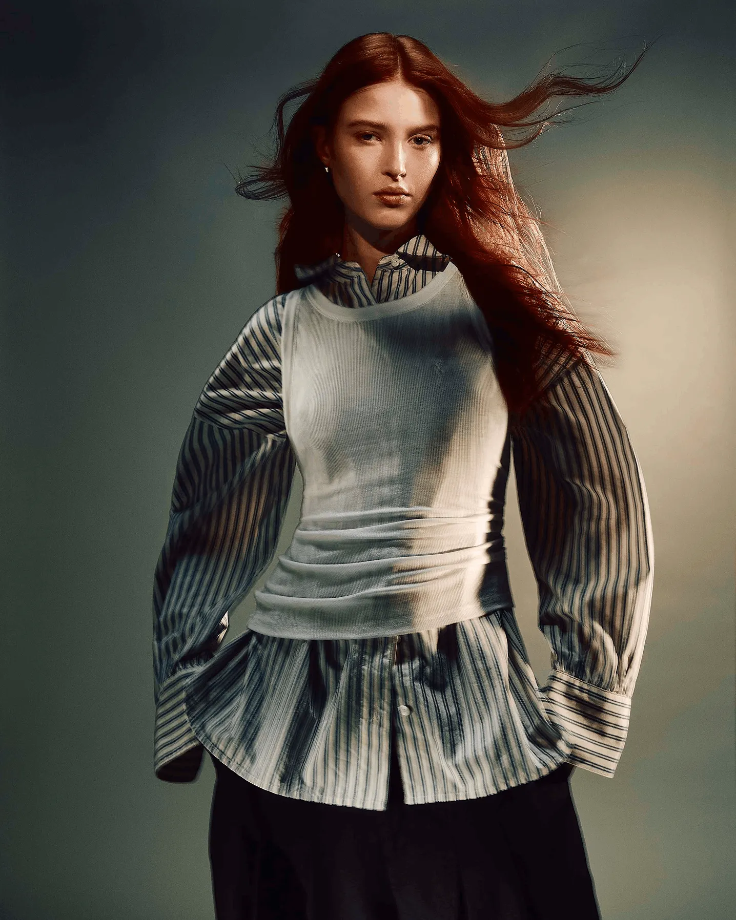 Women wearing a blue and white checked shirt with a white tank layered over in front of a grey background