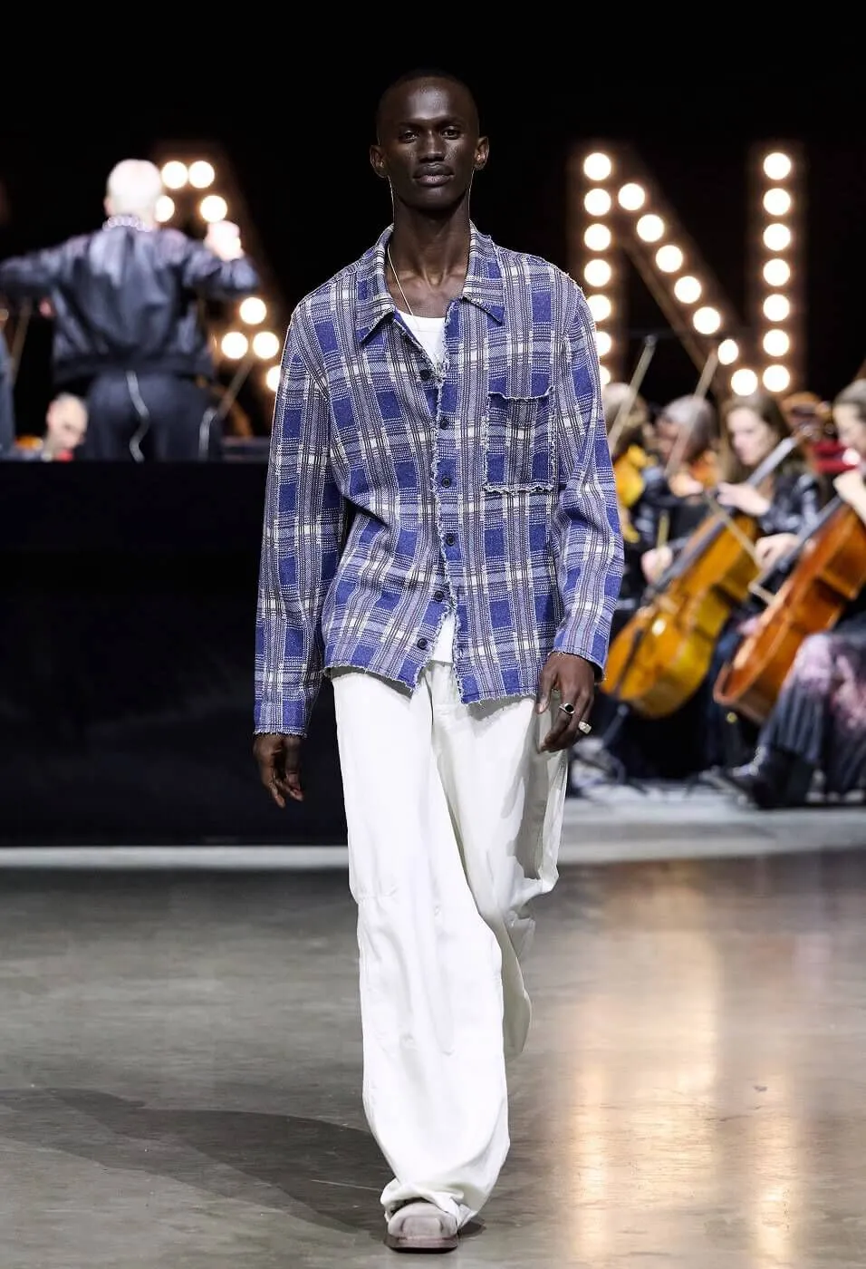 Man wearing checked blue shirt with white trousers