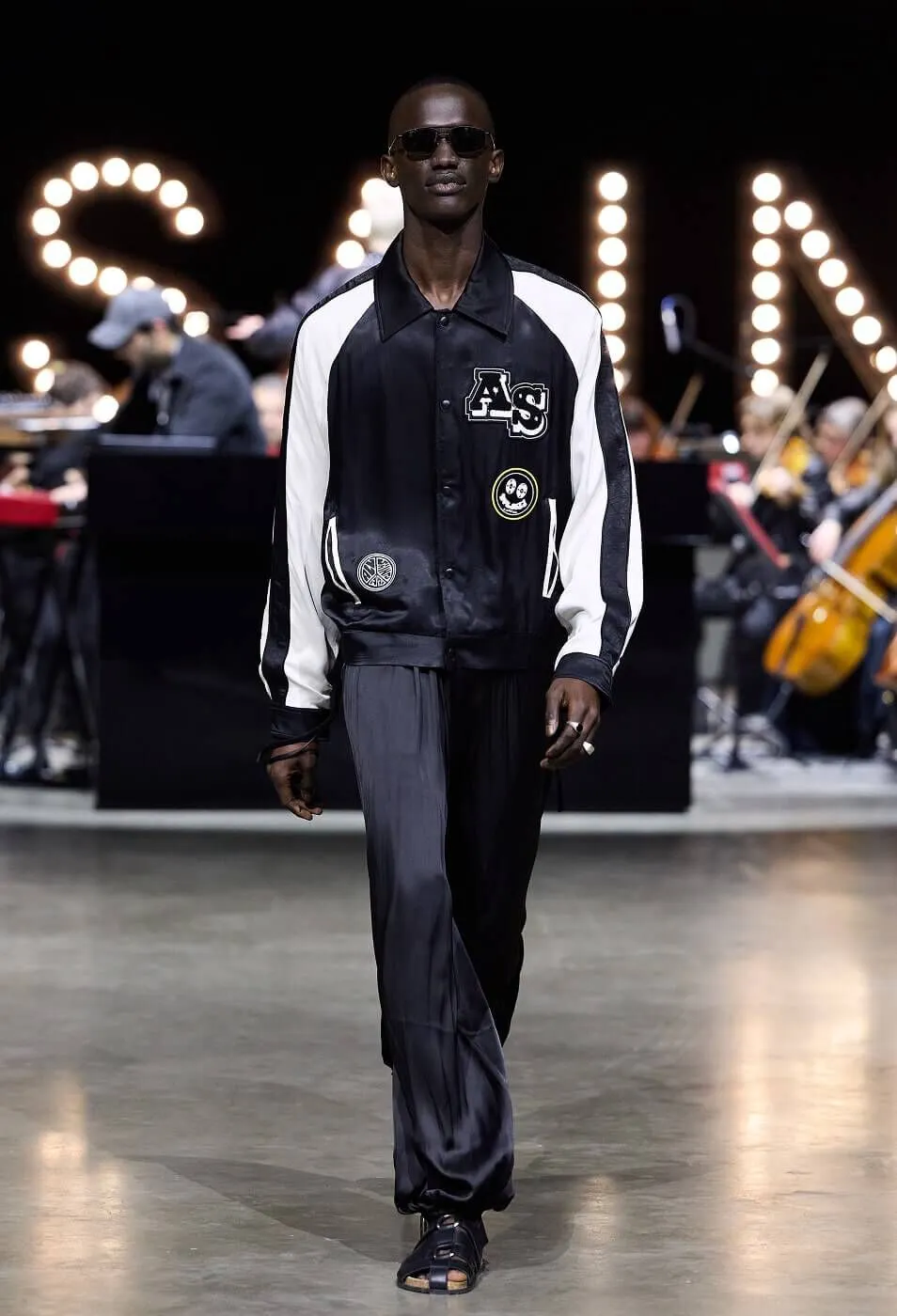 Man wearing black satin trousers with a black bomber jacket