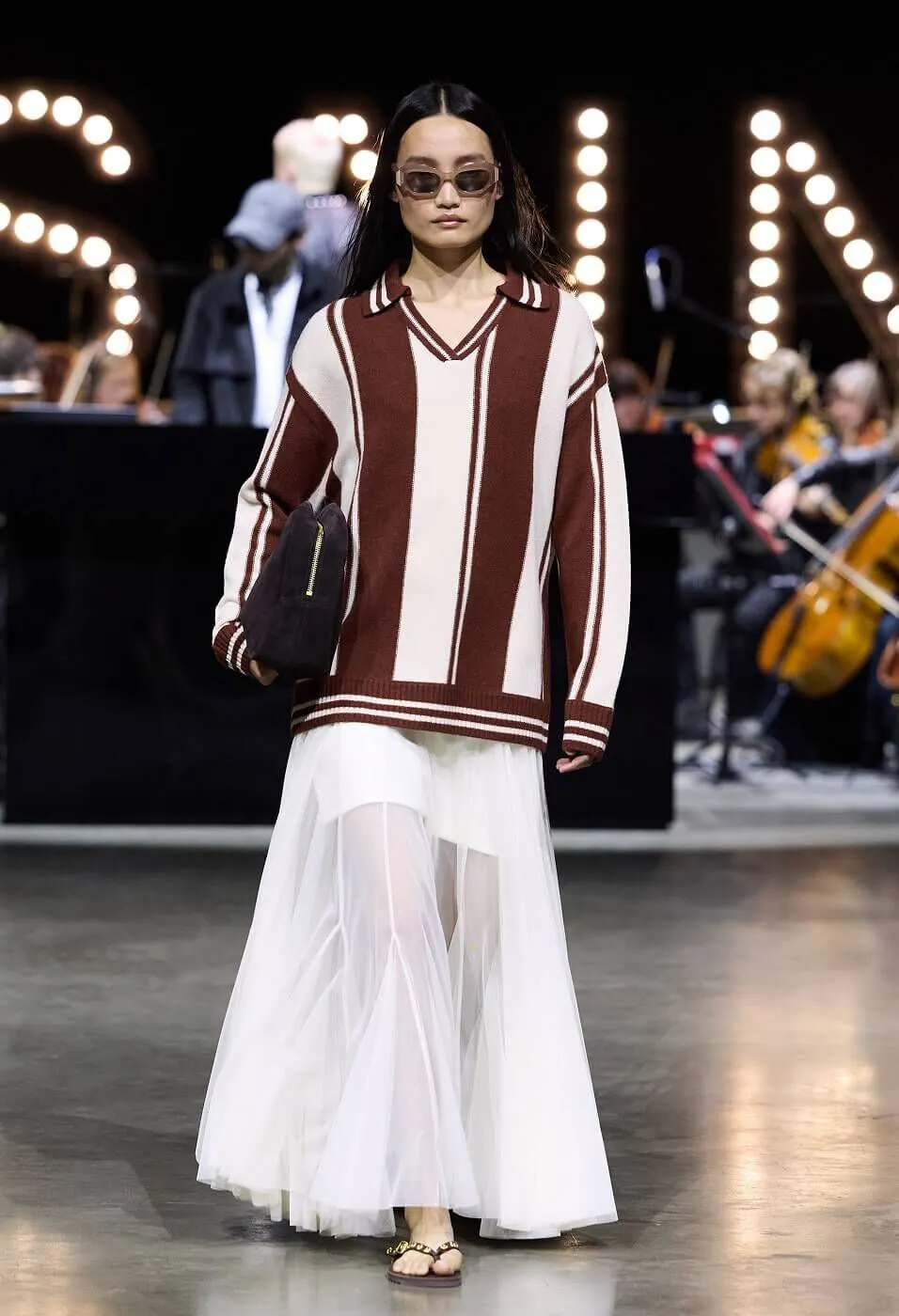 Woman wearing striped collared jumper with white sheer flowy skirt