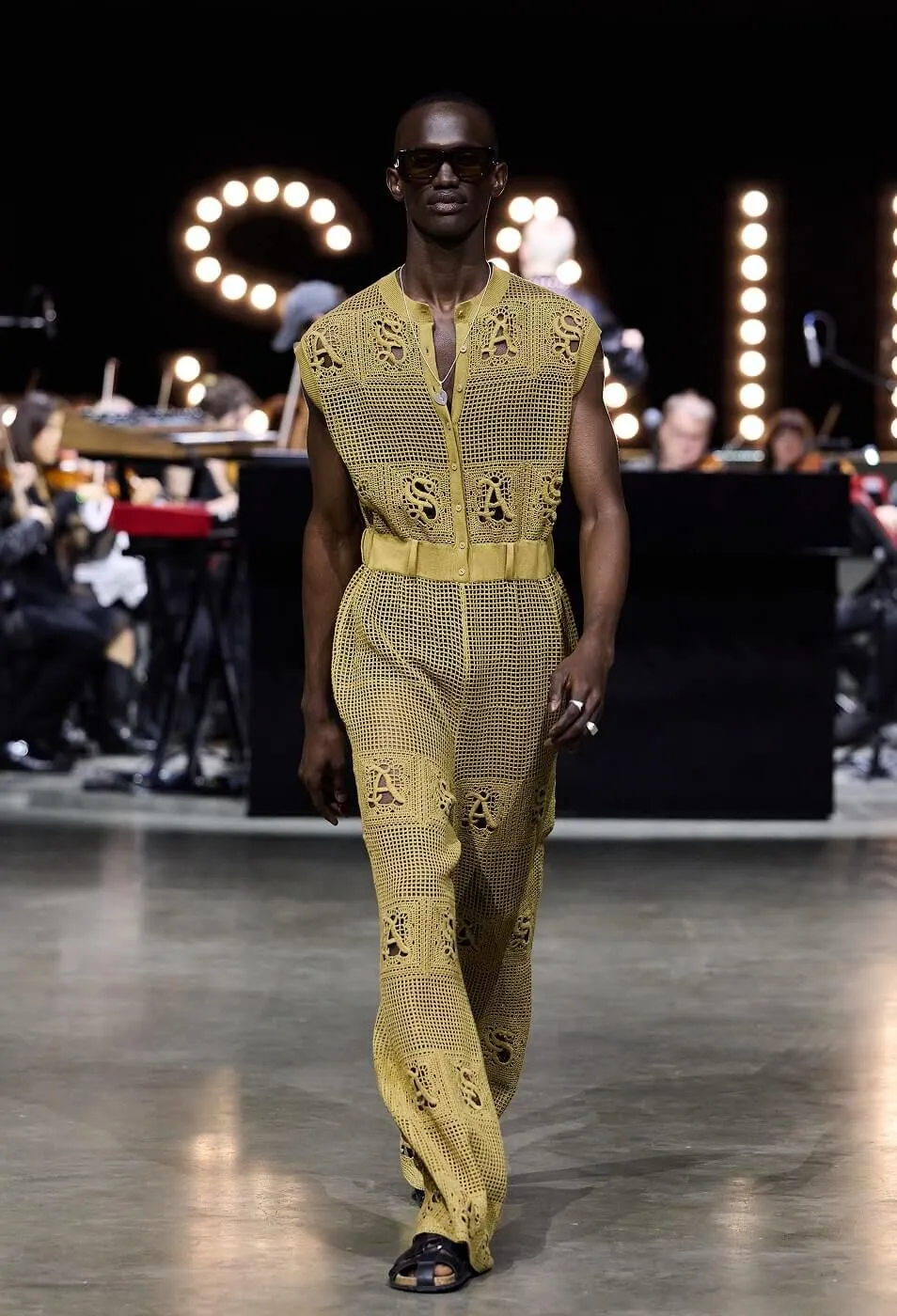 Man wearing yellow jumpsuit with black sandals