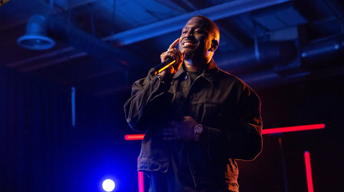 Ben Reilly standing on stage smiling and holding a microphone