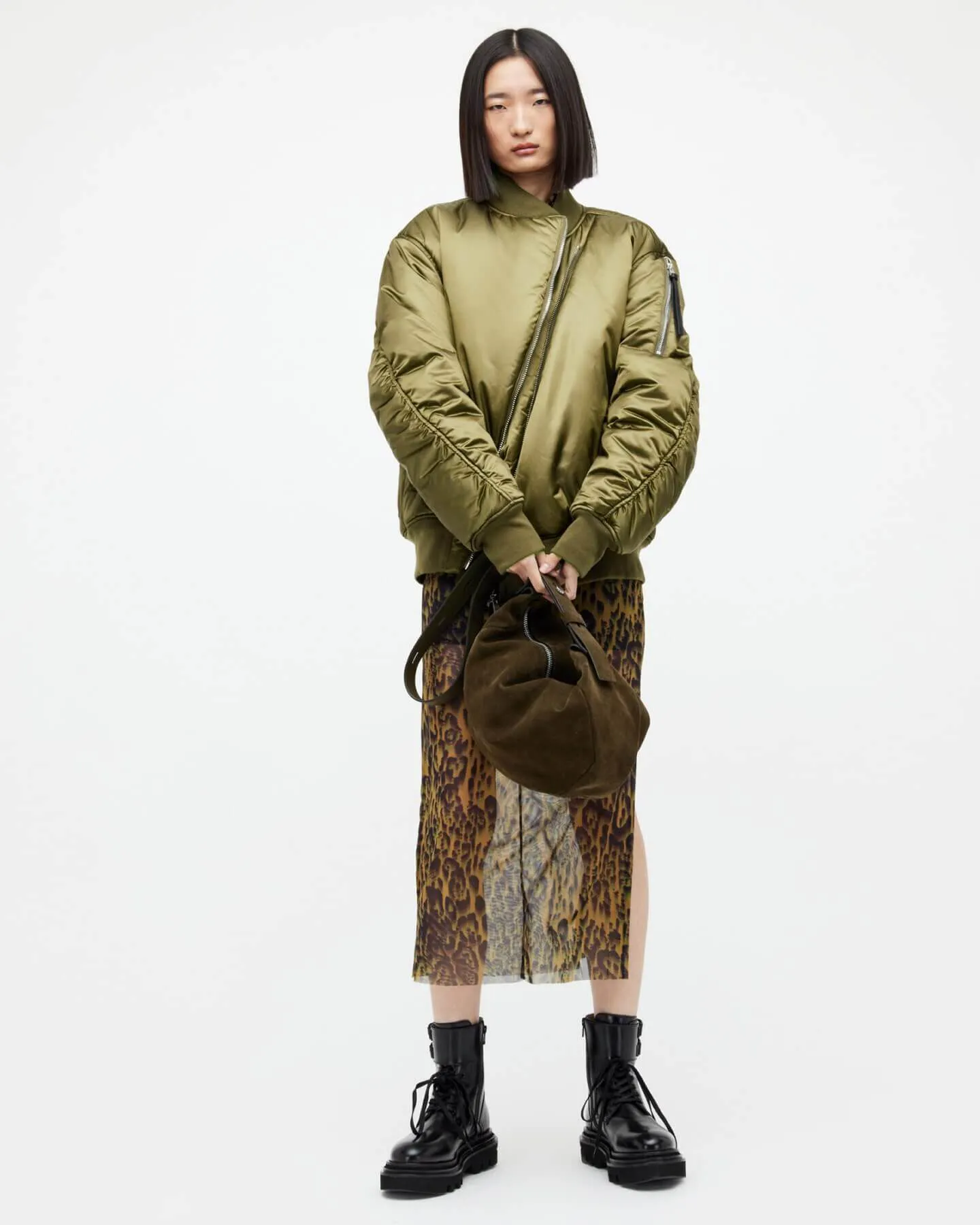 A woman wearing a khaki bomber and transparent skirt.
