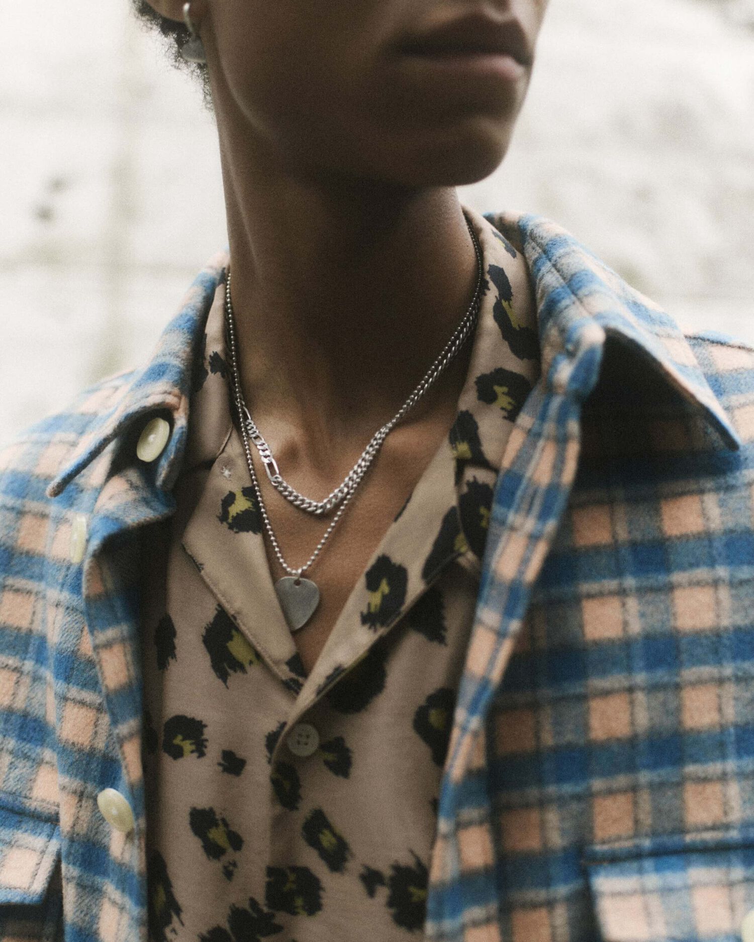 Portrait of a man wearing a blue checked shirt over a leopard print one.