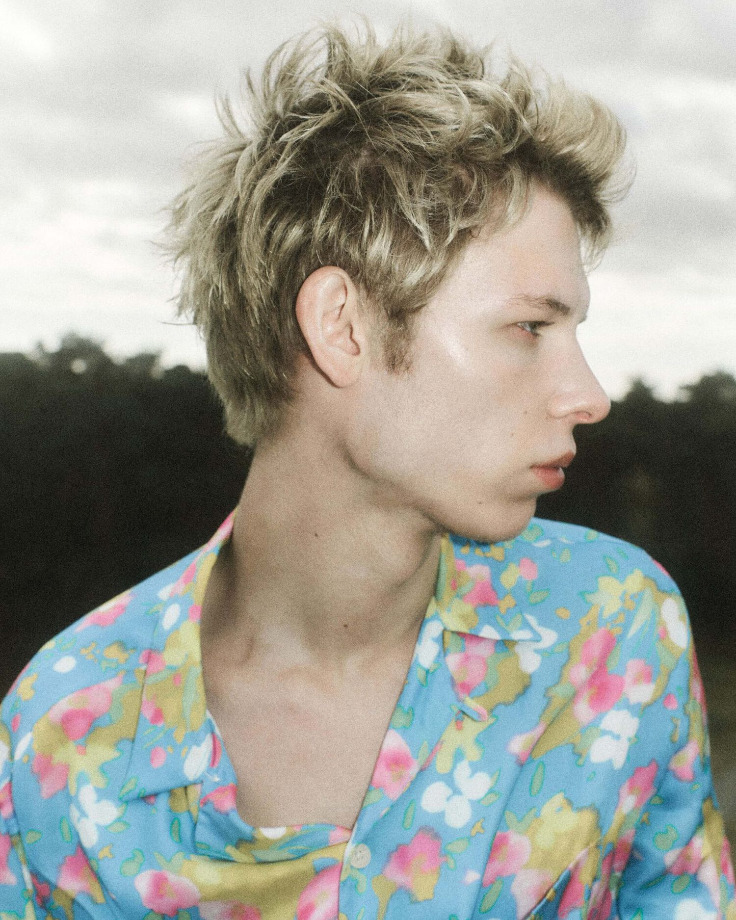 Portrait of a man wearing a flower printed blue Hawaiian shirt.